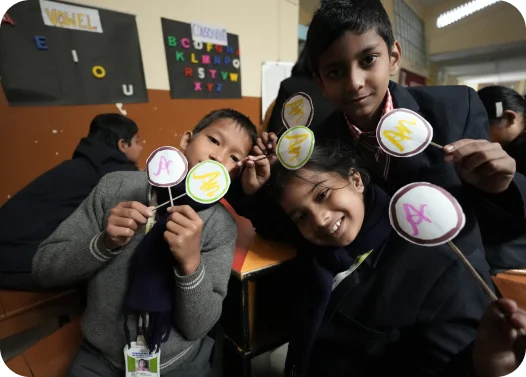 Students holding up signs with science symbols in a classroom.