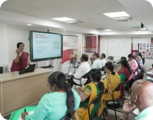 A presenter leading a corporate training session in a boardroom with attentive participants.