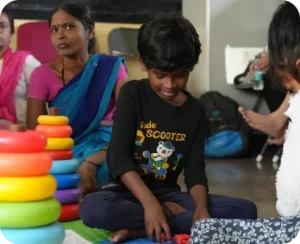 Child playing with colorful rings; people around in a room.