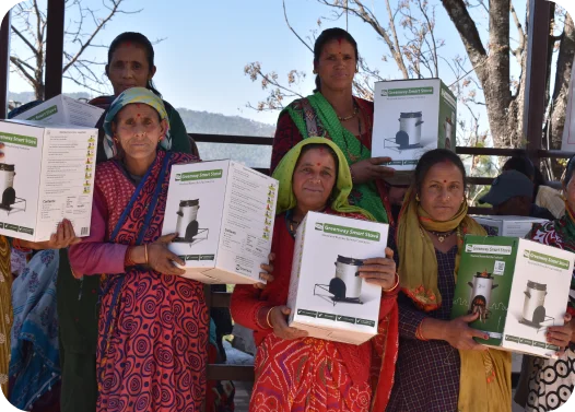 Group of individuals holding boxes of cooking stoves with trees in the background.