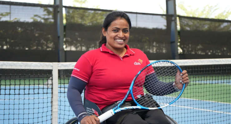 Wheelchair tennis player holding a racquet on the court.