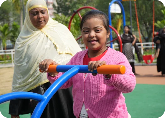 A child in a pink sweater playing on a blue and orange playground equipment.