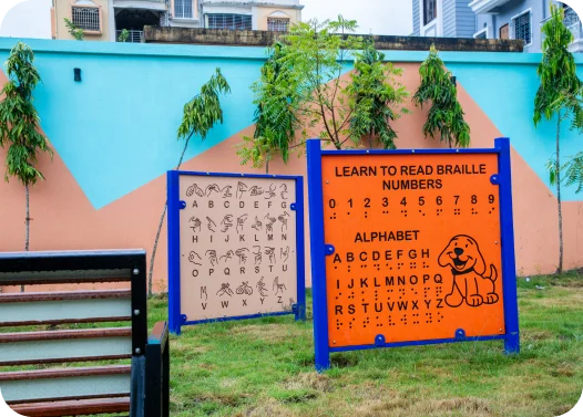 Outdoor Braille learning boards with numbers and alphabet next to a bench.