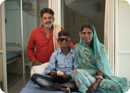 Three individuals seated on a hospital bed, with one holding an IV bag.