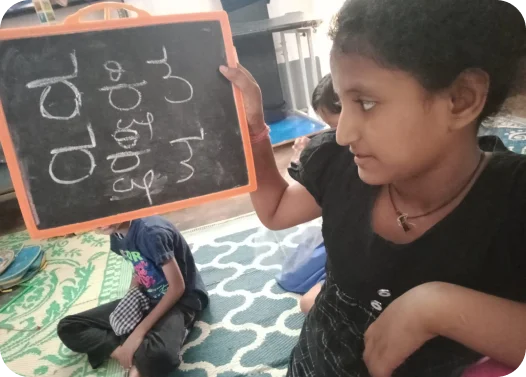 Person holding a chalkboard with writing, sitting on the floor with a child nearby.