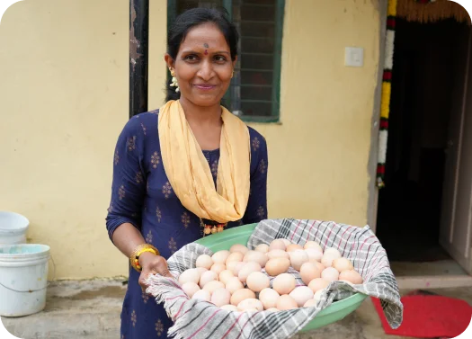 Person holding a tray full of eggs with a cloth underneath, standing outside a building.